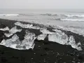 Lodowe bryły na czarnym piasku tworzą magiczną diamentową plażę Islandii. Fale oceanu delikatnie obmywają ten niezwykły krajobraz.
