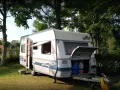 Przygotowania do wypoczynku na **camping Duszniki Zdrój**. Przyczepa kempingowa z otwartym bagażnikiem, w którym widać butle gazowe.