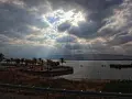 Słoneczne promienie przebijające się przez chmury nad jeziorem, palmy na brzegu. Taka pogoda w Egipcie w sierpniu to rzadkość.