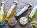 Bottiglie di olio d'oliva, semi di girasole, semi di lino e olive. Scopri il miglior olio per friggere per le tue ricette.