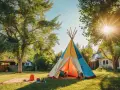 Un enfant joue dans un tipi coloré, parfait pour fabriquer un tipi extérieur en bois. Le soleil brille à travers les arbres.