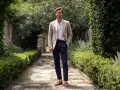 Uomo con giacca beige e pantaloni blu, un look che evoca un raffinato stile francese.
