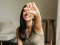 Une jeune femme souriante tient une capsule, symbole d'une cure de vitamine pour un bien-être quotidien.