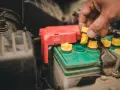 A hand removes a yellow cap from a truck battery, hinting at maintenance to ensure it lasts as long as possible.