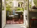 Schmaler Balkon Ideen: Gemütliche Sitzecke mit Tisch und Stühlen, umgeben von üppigem Grün. Perfekt für kleine Räume.