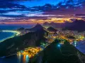 Zachód słońca nad słynną plażą w Rio de Janeiro. Miasto rozświetlone tysiącami świateł, góry i ocean tworzą magiczny widok.