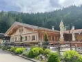 Holzhütte mit Biergarten und blühenden Blumen vor einer Bergkulisse. Die untere Firstalm lädt zum Verweilen ein.