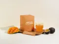 Pudełko kolagenu rybiego o smaku mango-marakuja, szklanka napoju, kawałek mango i marakuja. Wsparcie dla fibroblastów i zdrowej skóry.