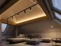 Accogliente mansarda con tetto spiovente, illuminazione a faretti e luce d'ambiente calda.