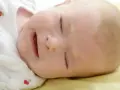 Słodkie niemowlę płacze przez sen, z otwartymi ustami i zamkniętymi oczami.