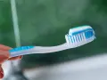 Dłoń trzymająca szczoteczkę z biało-niebieską pastą. Idealna jaka pasta po wybielaniu zębów dla lśniącego uśmiechu.