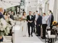 Para idzie do ołtarza, składając przysięgę małżeńską cywilną. Panna młoda w białej sukni, pan młody w granatowym garniturze.
