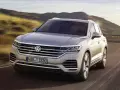 Elegancki Volkswagen Touareg, jeden z wielu imponujących volkswagen modele, pędzi po krętej drodze wśród wzgórz.
