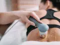 Therapeutin führt Ultraschall Physiotherapie am Rücken einer Patientin durch. Gel auf der Haut für die Behandlung.