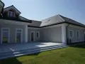 Nowoczesny dom z tarasem i trawnikiem. Elegancki gzyms podkreśla architekturę budynku.