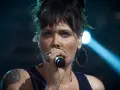 Beth Hart z tatuażem na ramieniu, w okrągłych kolczykach, śpiewa do mikrofonu. Choć nie widać jej dzieci, jej energia na scenie jest jak dla nich.