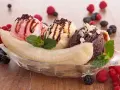 Ein klassisches Banana Split Eis mit drei Kugeln Eis, garniert mit Beeren und Schokostreuseln.