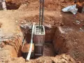 Wykop pod fundament słupowy, zbrojenie i szalunek gotowe do zalania betonem.