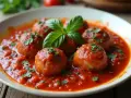 Pulpety w sosie pomidorowym jak u babci, udekorowane bazylią i natką pietruszki. Pyszne, domowe danie.