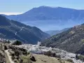 Malownicza wioska w górach Sierra Nevada, Hiszpania, z białymi domami i kościołem, w tle błękitne pasma górskie.