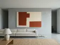 Un soggiorno minimalista con un divano bianco, un tappeto in juta e un quadro astratto su pareti colorate moderne.