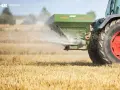 Traktor rozsiewa wapno magnezowe na polu.