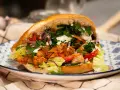Pyszny, domowy kebab z kurczaka z piekarnika, pełen świeżych warzyw i sosu, na ozdobnym talerzu.