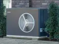 Nowoczesna pompa ciepła, która obniża koszt ogrzewania domu. Urządzenie stoi na fundamencie, otoczone zielenią.