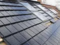 Dachziegel mit integrierten Solarzellen, die eine moderne Alternative zu herkömmlichen Ziegeln darstellen. Die Frage "was kostet ein Dachziegel" wird hier durch die innovative Technologie beantwortet.