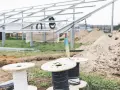 Na placu budowy paneli słonecznych przygotowywane są kable do uziemienia. Widać szpule z przewodami i metalowe konstrukcje.
