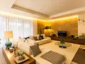 Salón moderno con sofá blanco, mesa de centro de cristal y **luz indirecta** que ilumina la pared de piedra y las cortinas.