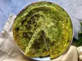 Frittata di zucchine in padella, dorata e profumata, con una fetta tagliata per mostrare la morbidezza interna.