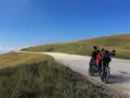 Ducati rossa ferma su strada sterrata, con un passo branchetto sullo sfondo e cielo azzurro.