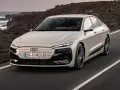 Jasnoszary Audi A6 e-tron jedzie po drodze z widokiem na ocean i góry.