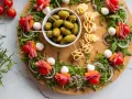 Kolorowa deska z przekąskami: szaszłyki z pomidorkami, mozzarellą, salami i marchewką, oliwki, ser. Idealne finger food przepisy na imprezę.