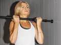 En kvinna med blont hår utför chin ups vid en stång.