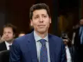 Mężczyzna w niebieskiej marynarce, który mógłby być jednym z twórców ChatGPT, siedzi przed mikrofonem.