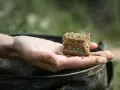 Gotowy do łowienia karpia metodą na karpia z gruntu. Wędkarz trzyma w dłoni podajnik z zanętą.