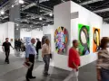 Visiteurs déambulant dans une foire d'art, découvrant des œuvres colorées et des sculptures. On y voit comment fonctionne une galerie d'art : présentation, exposition et interaction.