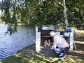 Man tänder en brasa i en nybyggd grill av tegelstenar vid en sjö.