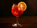 Ett glas Campari Spritz med is och en apelsinskiva, perfekt för en solig dag.