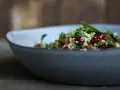 Frischer Tabouleh-Salat mit Granatapfelkernen in einer grauen Schüssel. Ein köstliches Rezept für den Sommer.