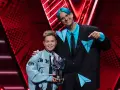 Chłopiec z błękitną kurtką i trofeum w kształcie dłoni, obok mężczyzny z niebieskimi włosami. To on wygrał The Voice Kids!
