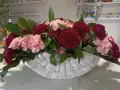 Piękne kompozycje z goździków w koszu. Różowe i bordowe kwiaty z zielonymi liśćmi tworzą elegancką całość.
