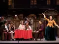 Scena z operetki. Kobieta w żółtej sukni śpiewa na tle kawiarni "Momus".