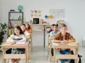 Uczniowie siedzą w ławkach w klasie, która wygląda jak szkoła średnia w Niemczech.