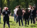 Groupe de jeunes adultes debout dans un champ verdoyant, certains se regardent.