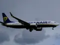 Samolot Ryanair z logo na ogonie leci na tle pochmurnego nieba. Może to być symbol zmiany nazwiska, gdy pasażerowie zmieniają swoje dane przed podróżą.
