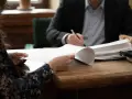 Rozmowa o dobrowolnych alimentach a potencjalnym działaniu komornika. Dwie osoby analizują dokumenty przy drewnianym stole.