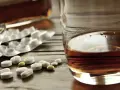 Tabletki i szklanka z alkoholem. Zastanawiasz się, po jakim czasie od zastrzyku można pić alkohol? To ważne pytanie.